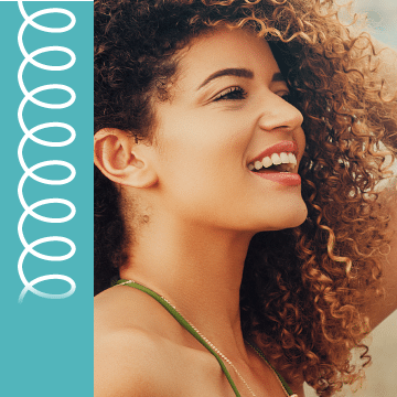 A woman with curly light brown hair smiles.