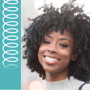 A woman with black curly hair smiles.